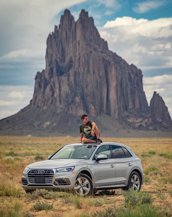 Portrait atop a car beneath Shiprock